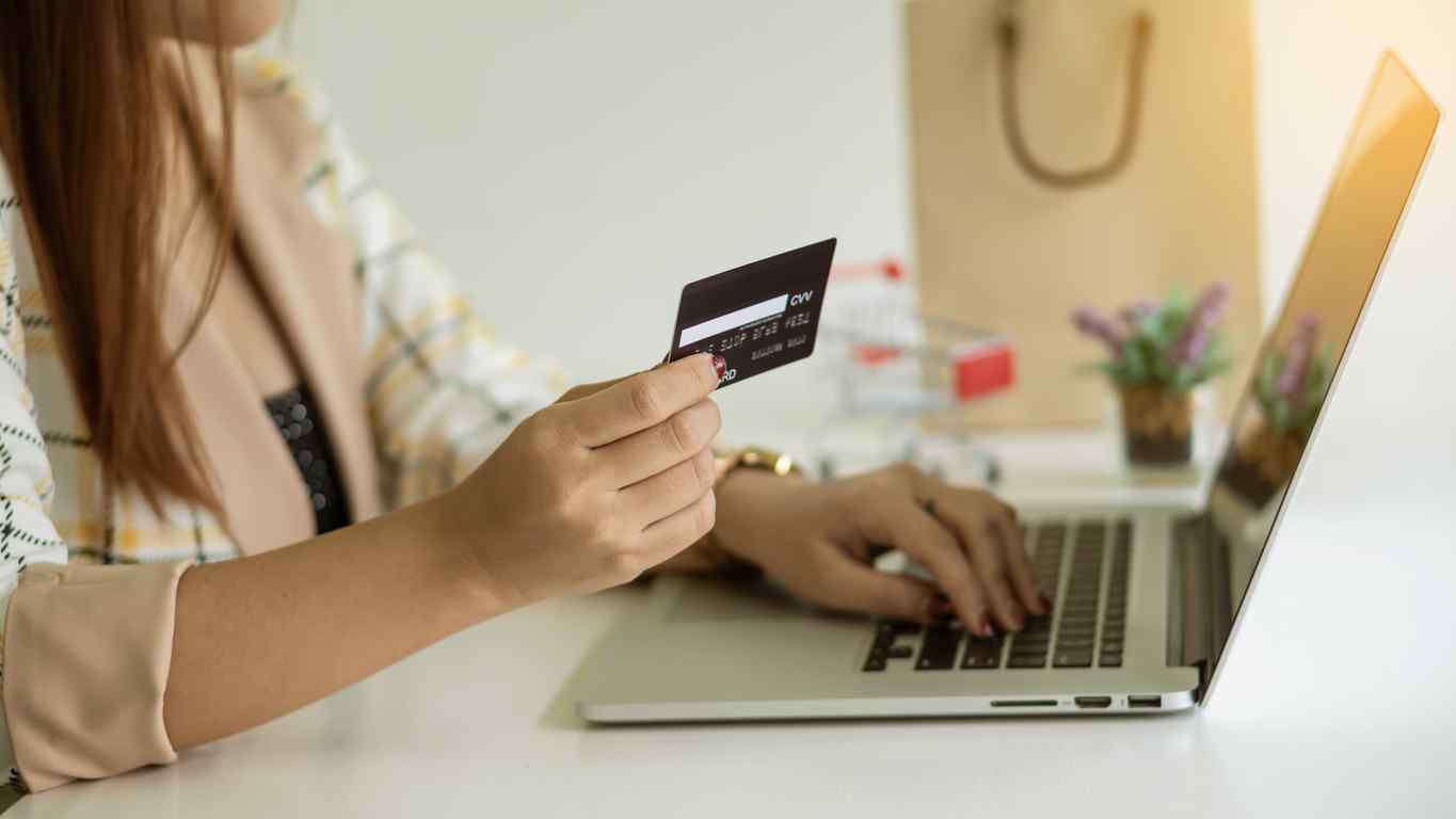 Woman typing prepaid debit card number into a laptop to activate the card.