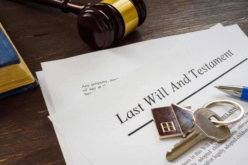 Last Will and Testament documents with a gavel, a set of keys, a pen, and a book on a wooden table